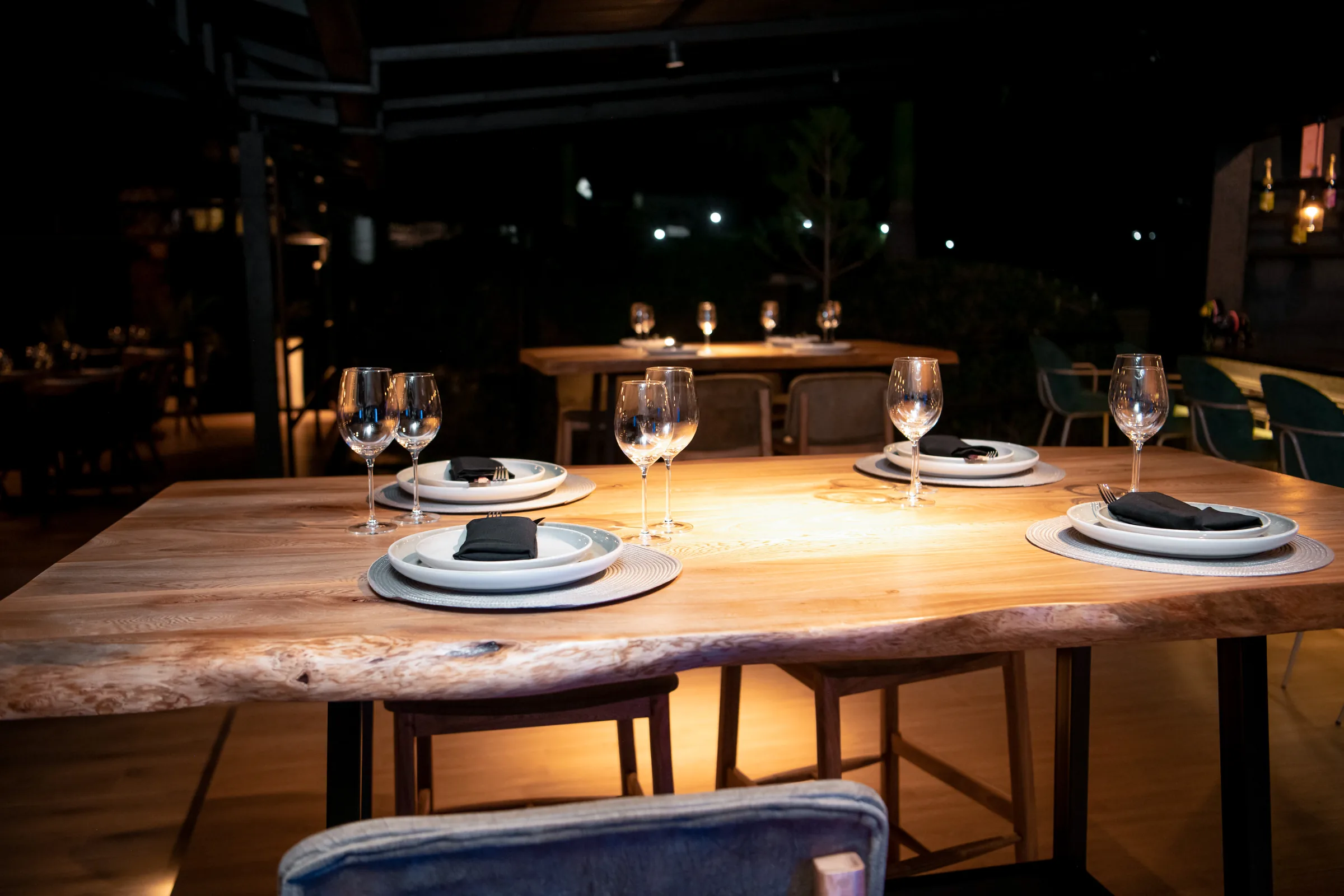 The terrace at Kultura after dark, a live edge timber table lit from above in a dark room